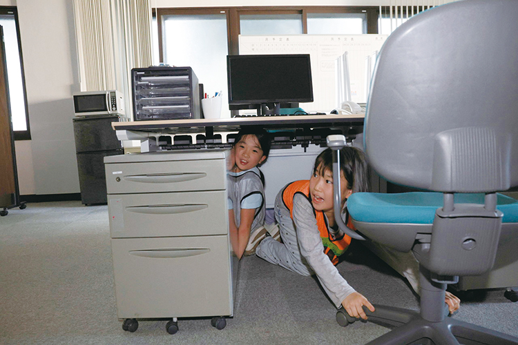 机の下に隠れる